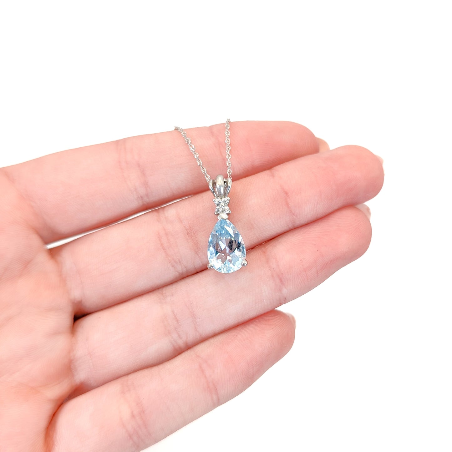 14k white gold necklace with a pear-shaped aquamarine gemstone pendant and diamonds on a white background