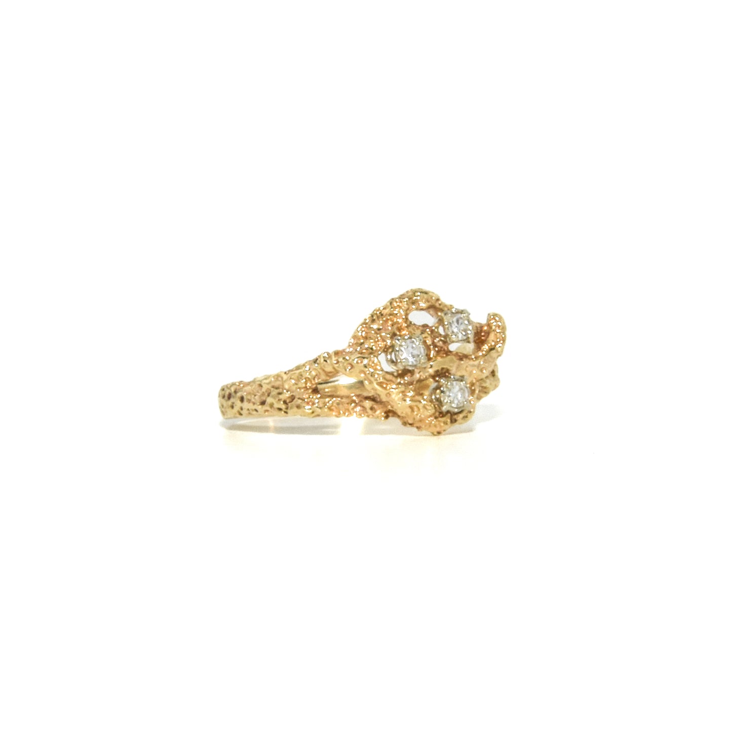 A vintage 14K gold Brutalist style ring with a textured design and three round-cut diamonds set within the gold structure.