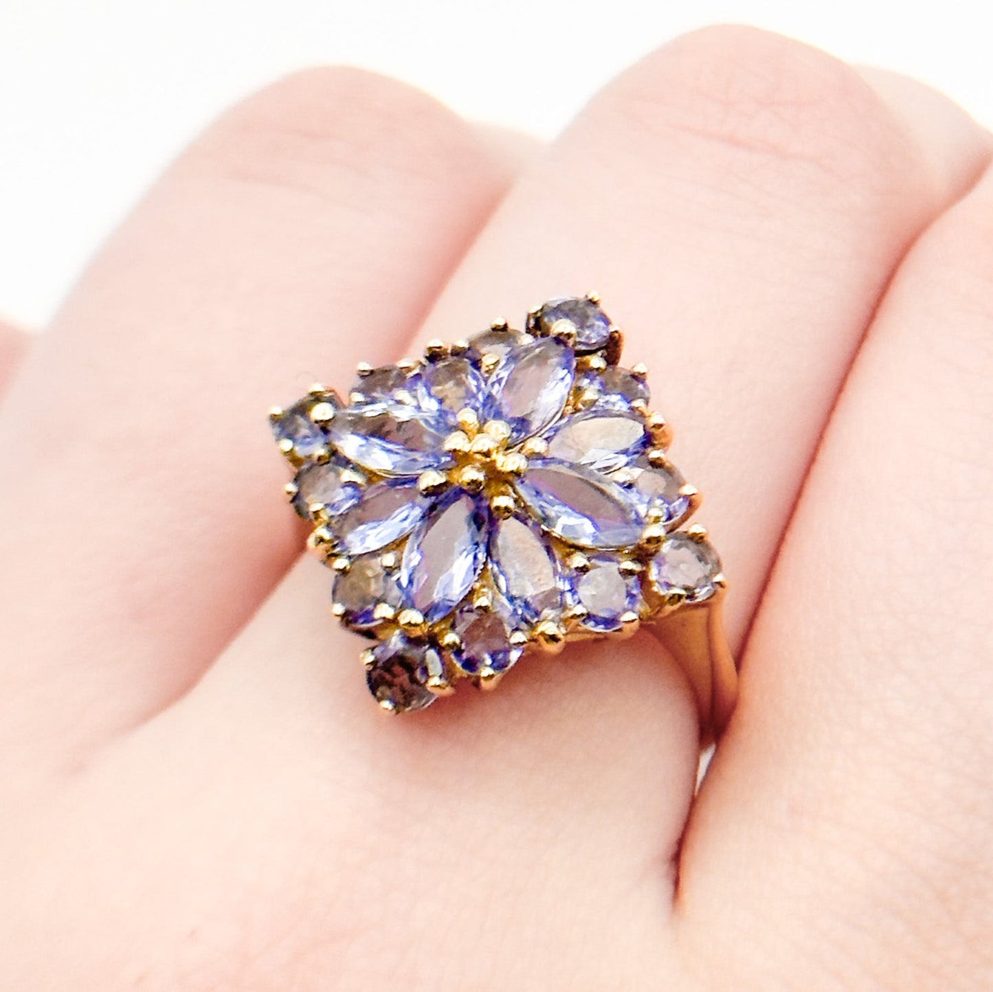 A vintage 14k gold cluster ring with multiple tanzanite gemstones set in a floral pattern.