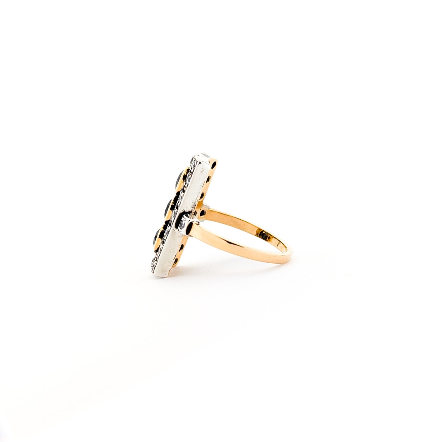 Elegant dinner ring, crafted in Italy, blends the warmth of 18K yellow gold with the cool brilliance of silver. The ring features a striking rectangular design with three deep blue sapphires, their rich color evoking the Mediterranean night sky against a white background.