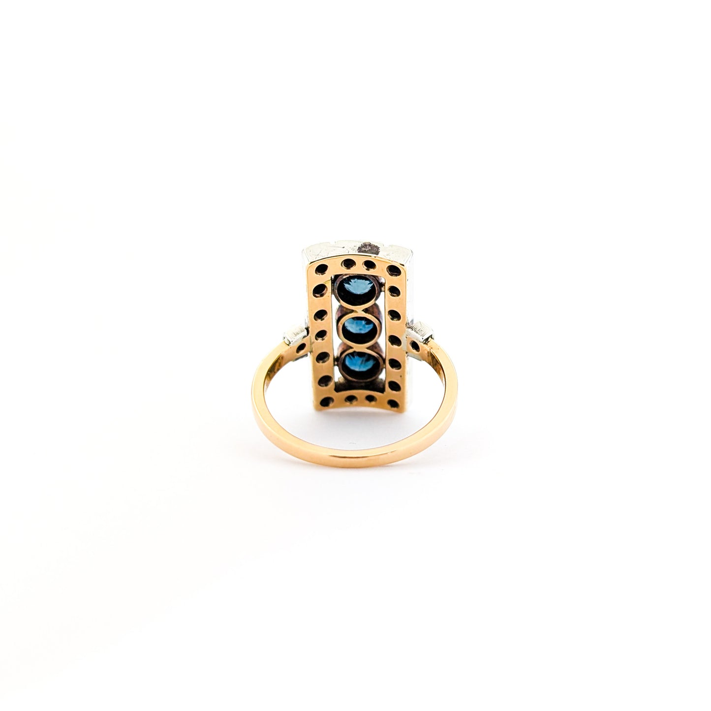 Elegant dinner ring, crafted in Italy, blends the warmth of 18K yellow gold with the cool brilliance of silver. The ring features a striking rectangular design with three deep blue sapphires, their rich color evoking the Mediterranean night sky against a white background.