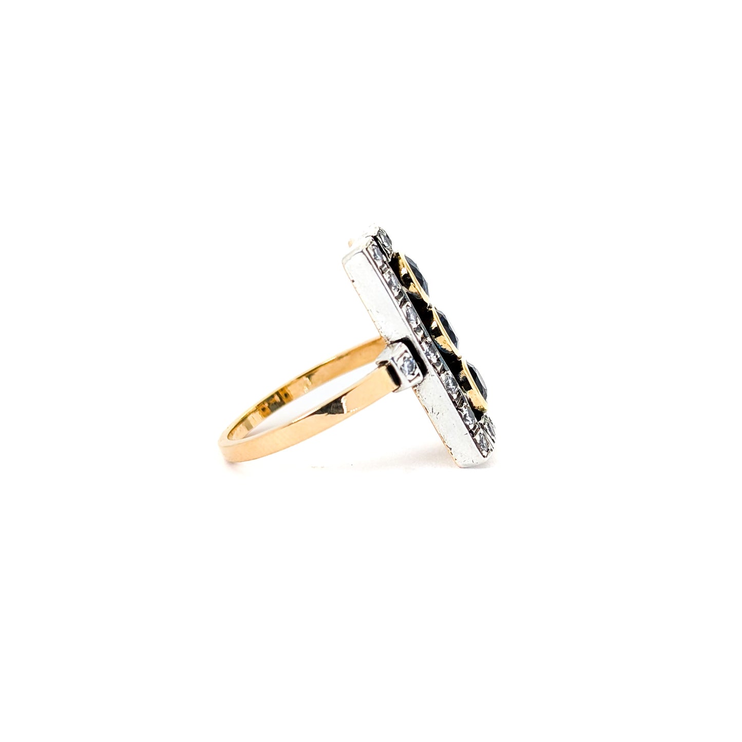 Elegant dinner ring, crafted in Italy, blends the warmth of 18K yellow gold with the cool brilliance of silver. The ring features a striking rectangular design with three deep blue sapphires, their rich color evoking the Mediterranean night sky against a white background.