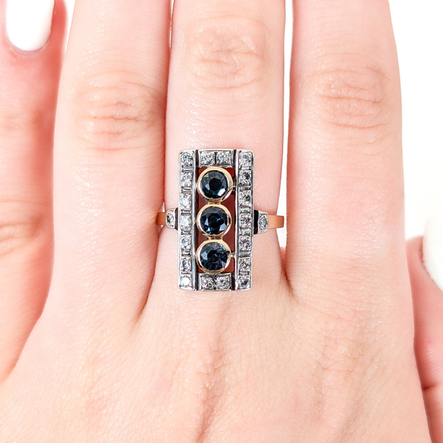Elegant dinner ring, crafted in Italy, blends the warmth of 18K yellow gold with the cool brilliance of silver. The ring features a striking rectangular design with three deep blue sapphires, their rich color evoking the Mediterranean night sky on a hand.