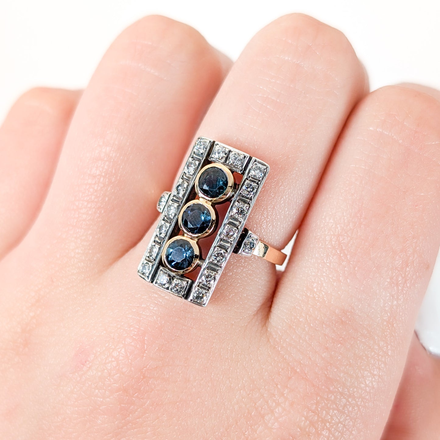 Elegant dinner ring, crafted in Italy, blends the warmth of 18K yellow gold with the cool brilliance of silver. The ring features a striking rectangular design with three deep blue sapphires, their rich color evoking the Mediterranean night sky on a finger.