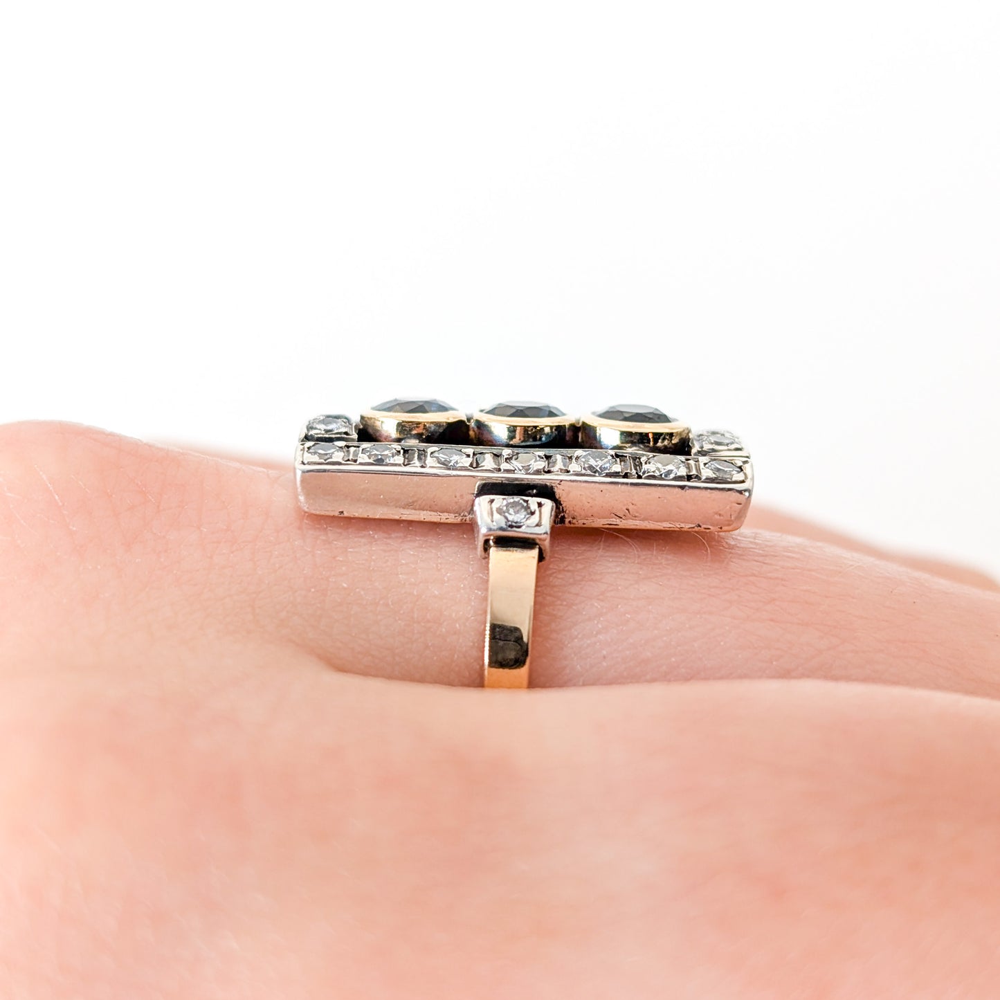 Elegant dinner ring, crafted in Italy, blends the warmth of 18K yellow gold with the cool brilliance of silver. The ring features a striking rectangular design with three deep blue sapphires, their rich color evoking the Mediterranean night sky on a finger.