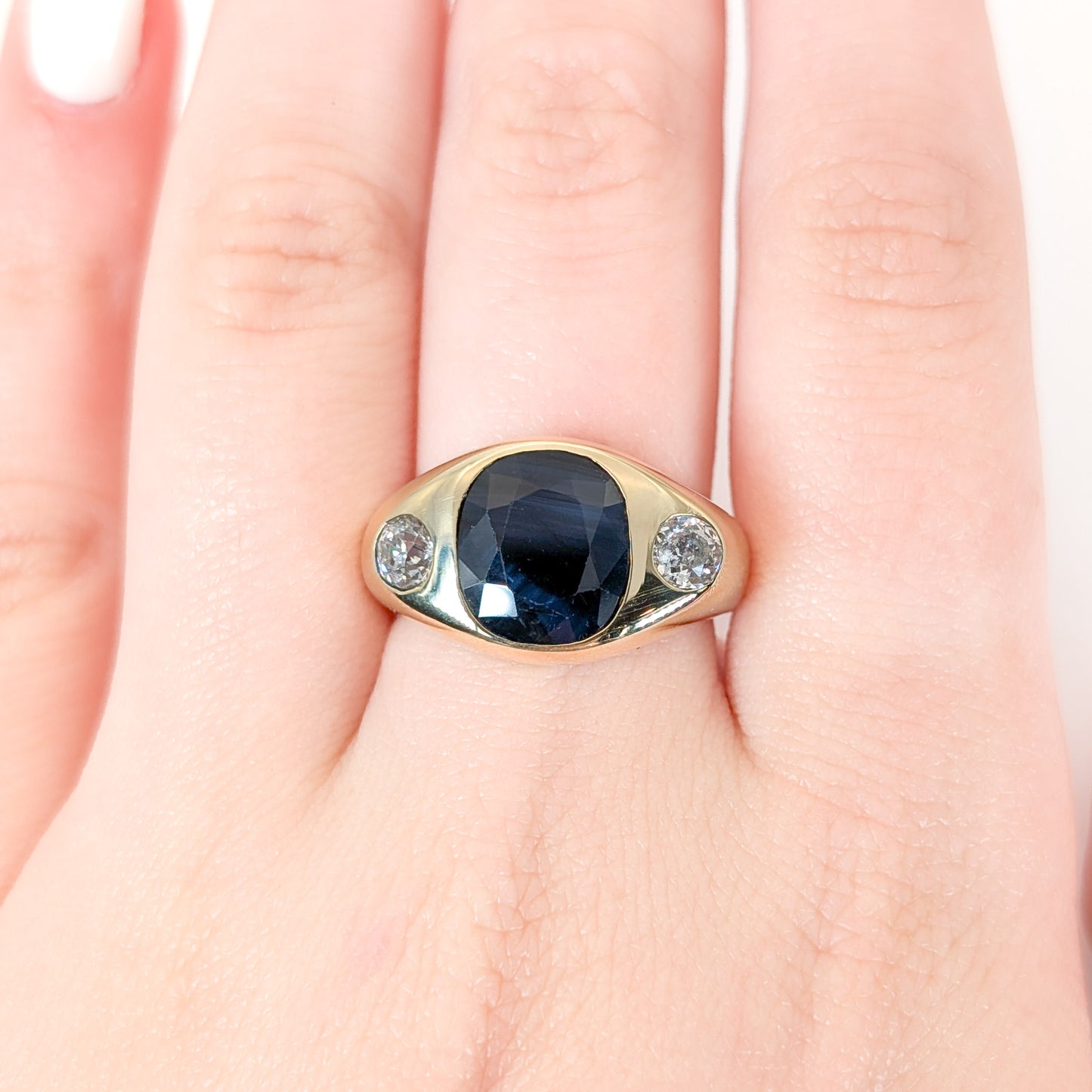 Italian crafted Antique Cushion Cut Blue Sapphire and Old Mine Cut Diamonds Dome Ring in 18K Gold with on a woman's hand white background