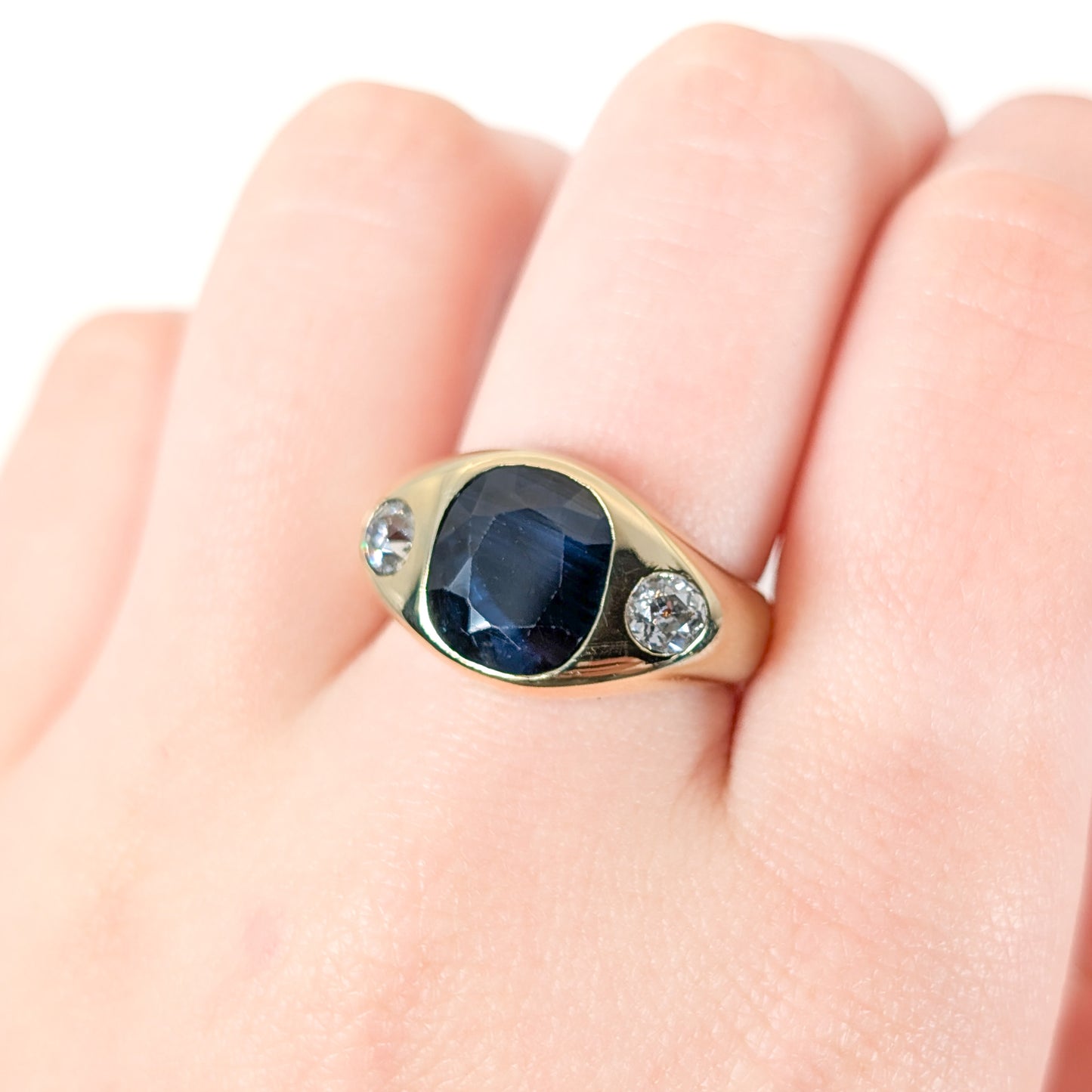 Italian crafted Antique Cushion Cut Blue Sapphire and Old Mine Cut Diamonds Dome Ring in 18K Gold with on a woman's hand white background