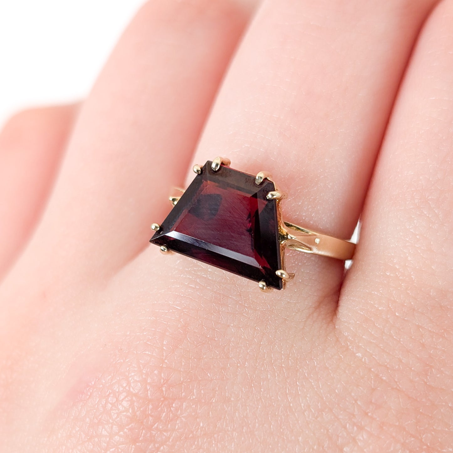 14K Gold garnet ring, cut into a striking trapezoid shape on a hand against a white background