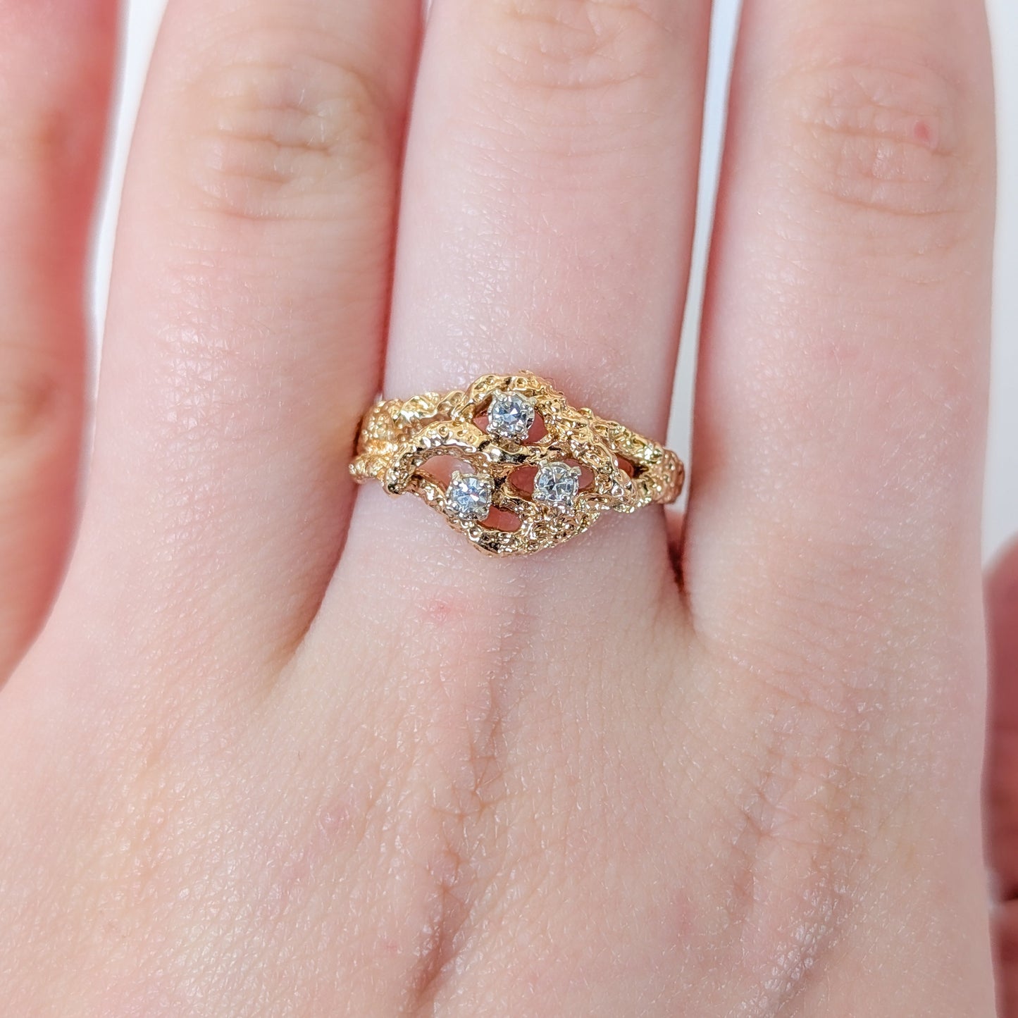 Gold ring with gemstones on a hand against a white background