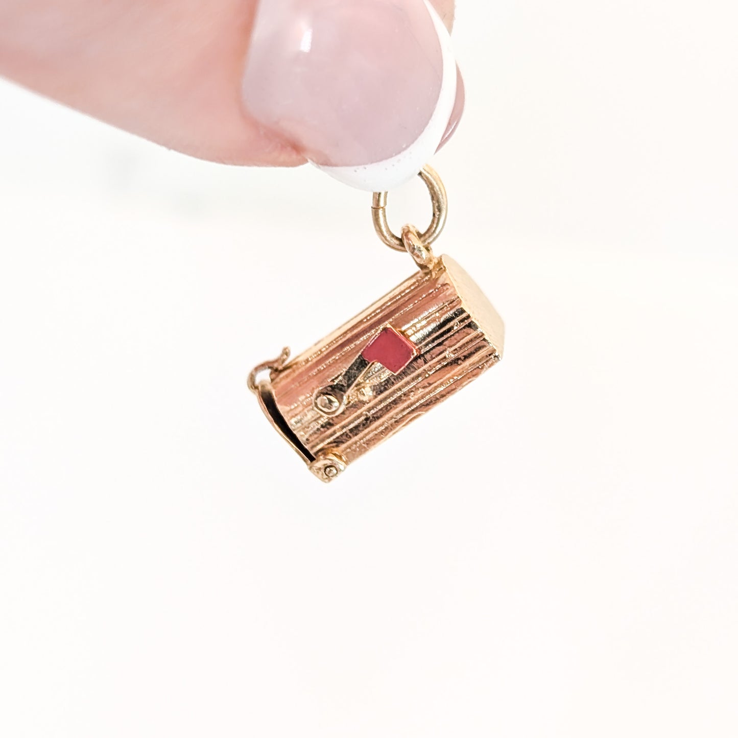 14k Gold U.S. Mail mailbox charm with enamel detailing, held by a hand on a white background