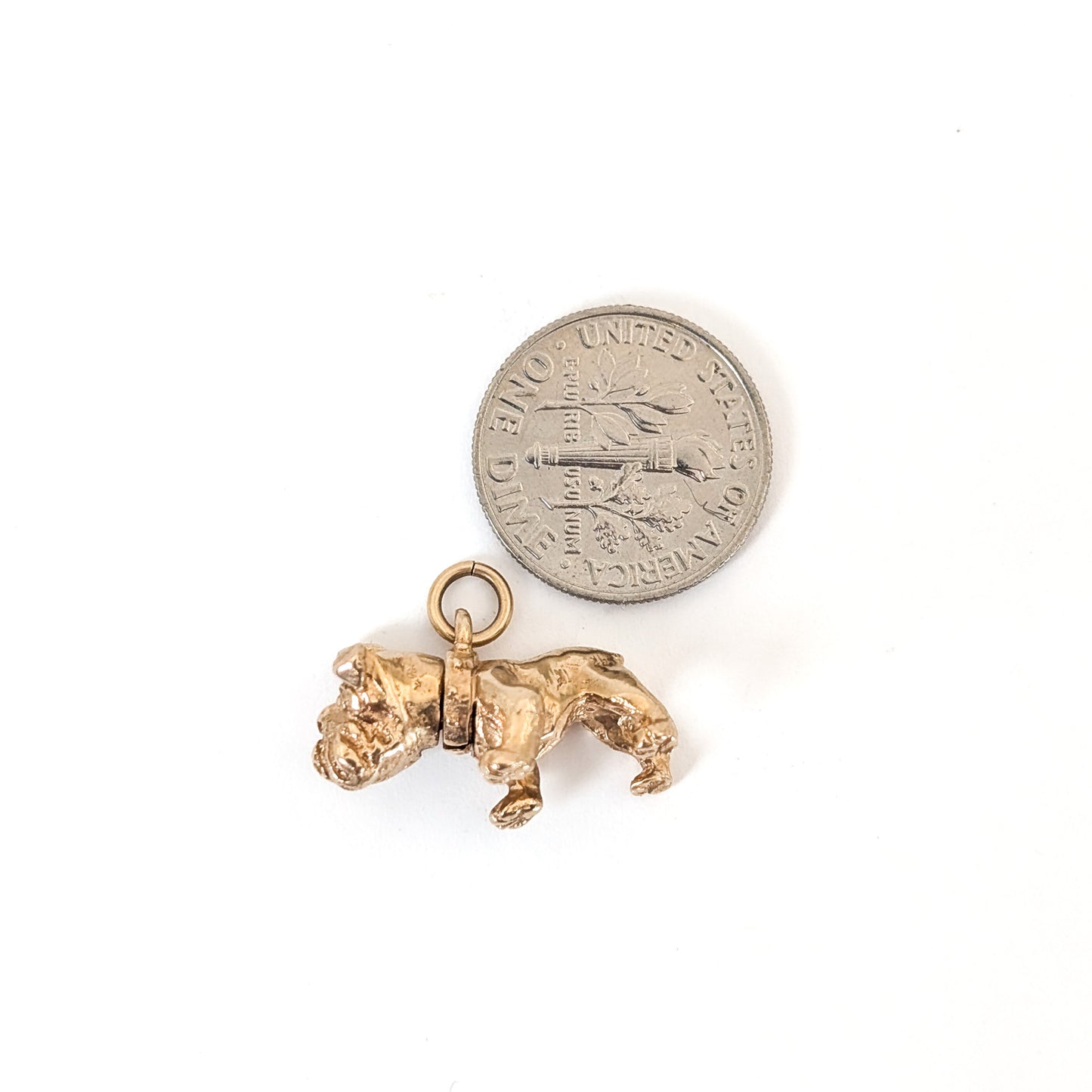 Vintage 14k Gold bulldog mechanical charm next to a U.S. quarter on a white background