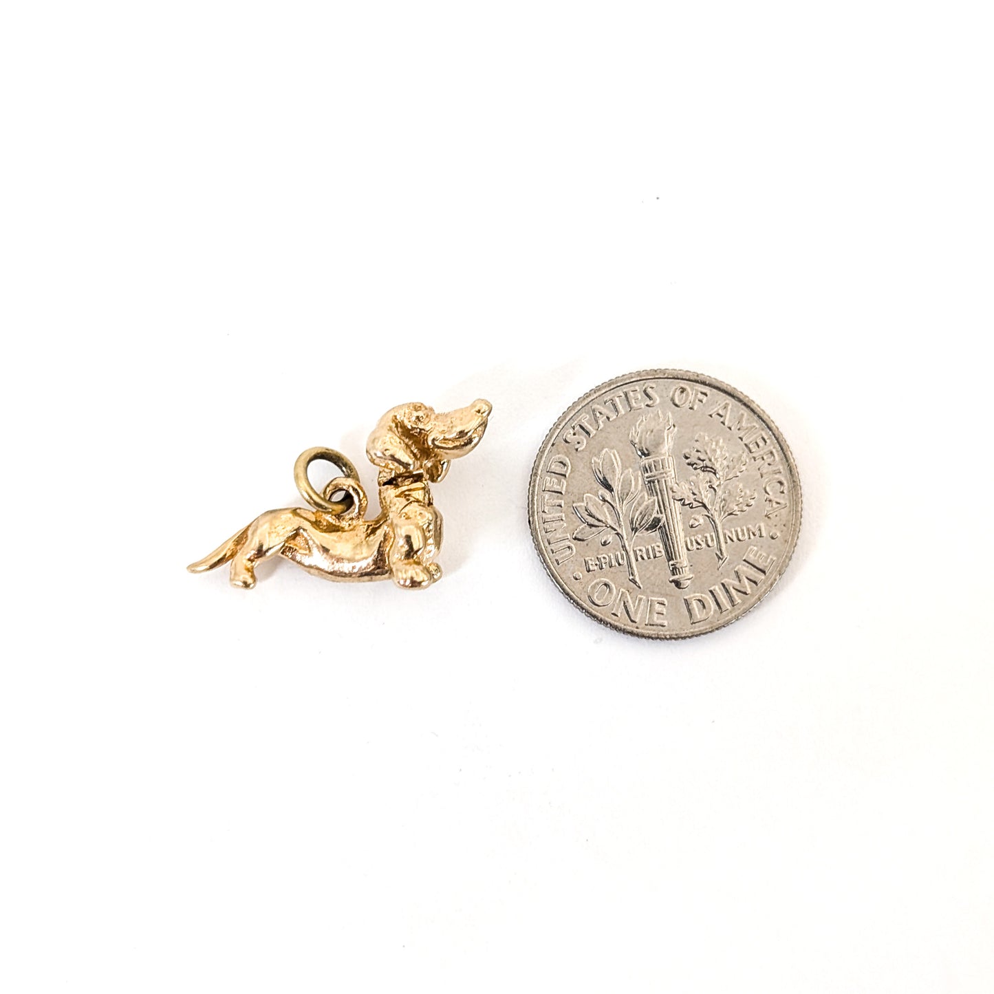 14K Gold dachshund mechanical charm next to a U.S. dime on a white background