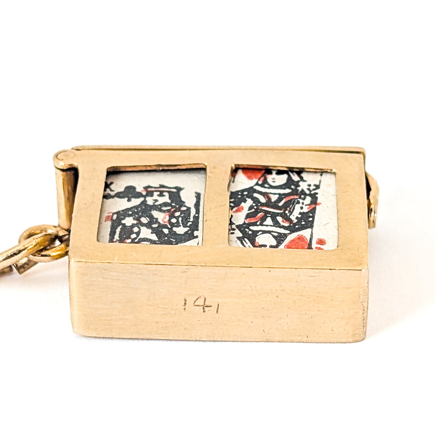 14k gold vintage mechanical charm with enameled card suit symbols and a real deck of cards on a white background