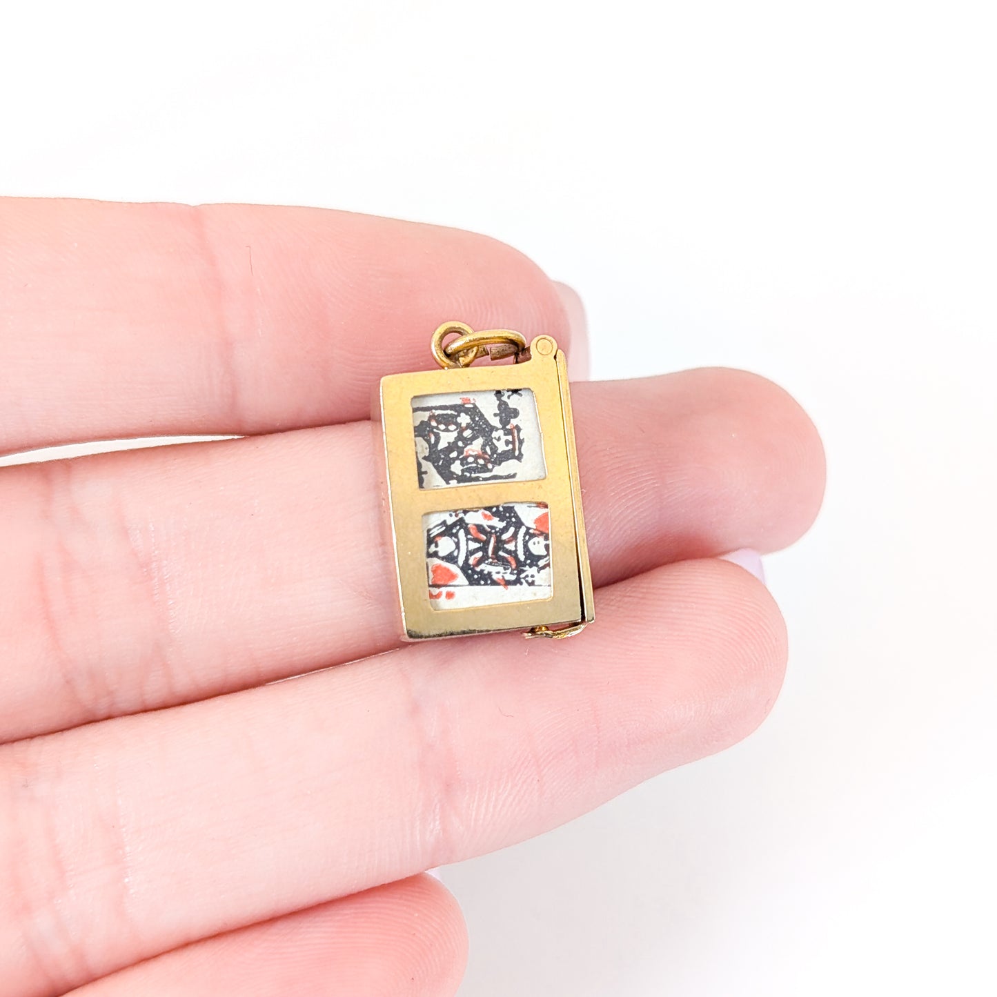 14k gold vintage mechanical charm with enameled card suit symbols and a real deck of cards on a white background
