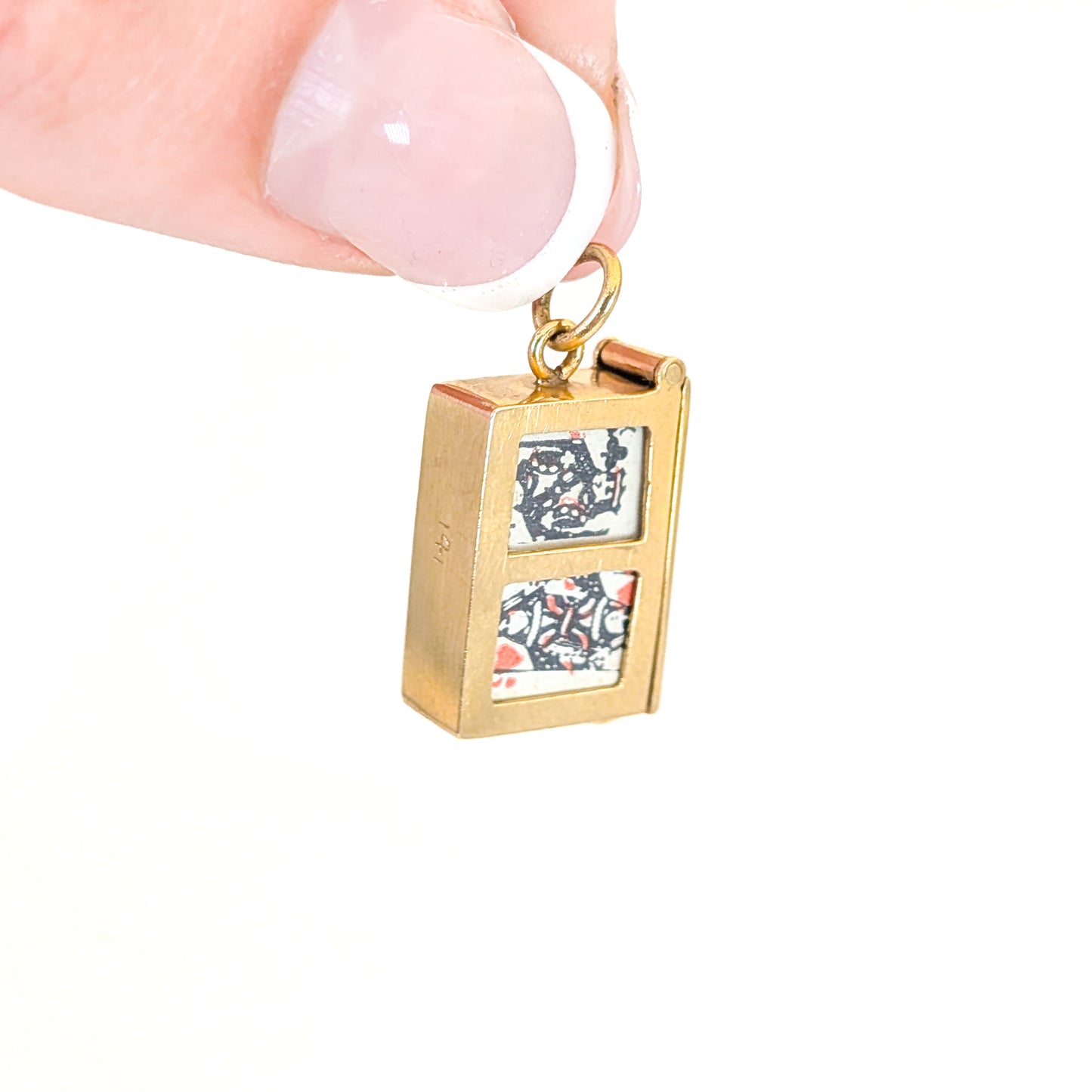 14k gold vintage mechanical charm with enameled card suit symbols and a real deck of cards on a white background