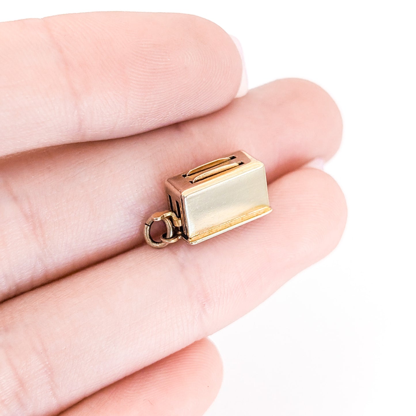 14k Gold toaster mechanical charm held between fingers on a white background