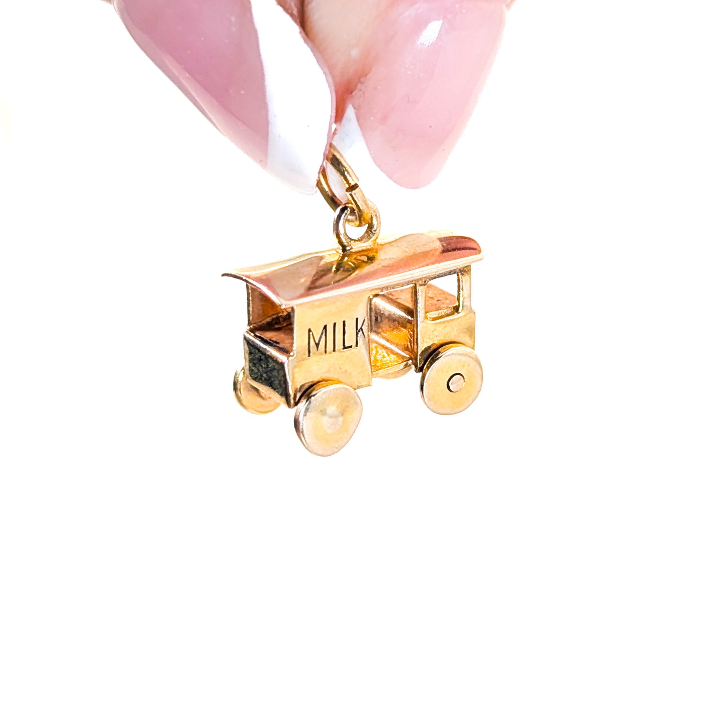 14K Gold milk cart mechanical charm held by a hand with pink nail polish on a white background