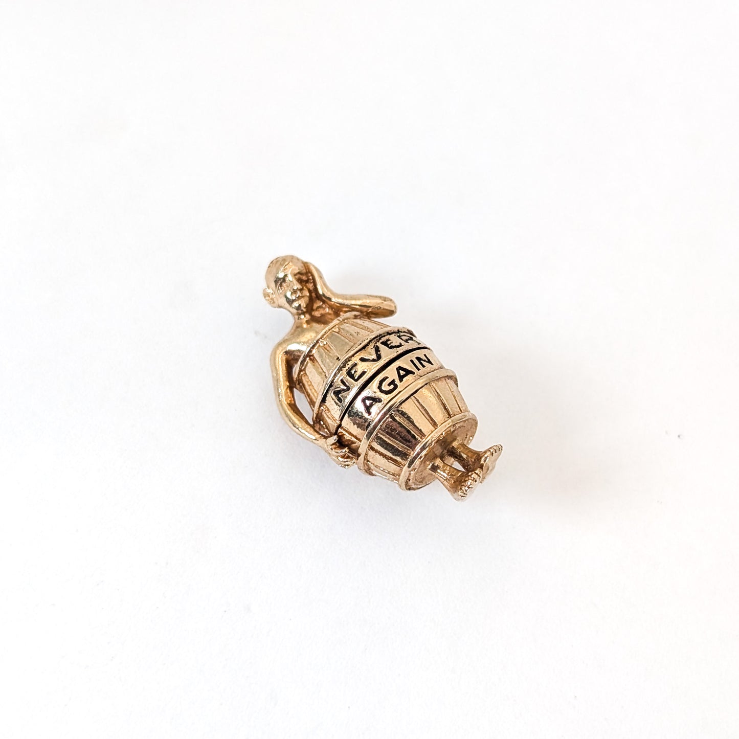 14K gold mechanical cram of a man in a barrel with 'Never Again' engraving on a white background