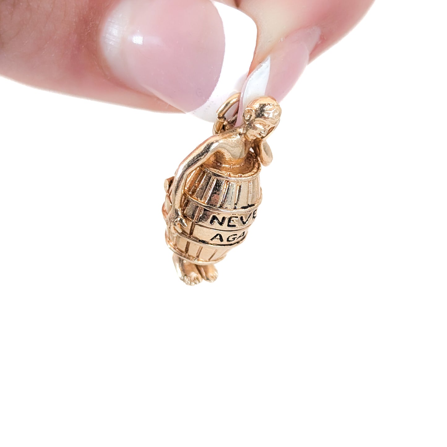 14K gold mechanical cram of a man in a barrel with 'Never Again' engraving held between fingers on a white background