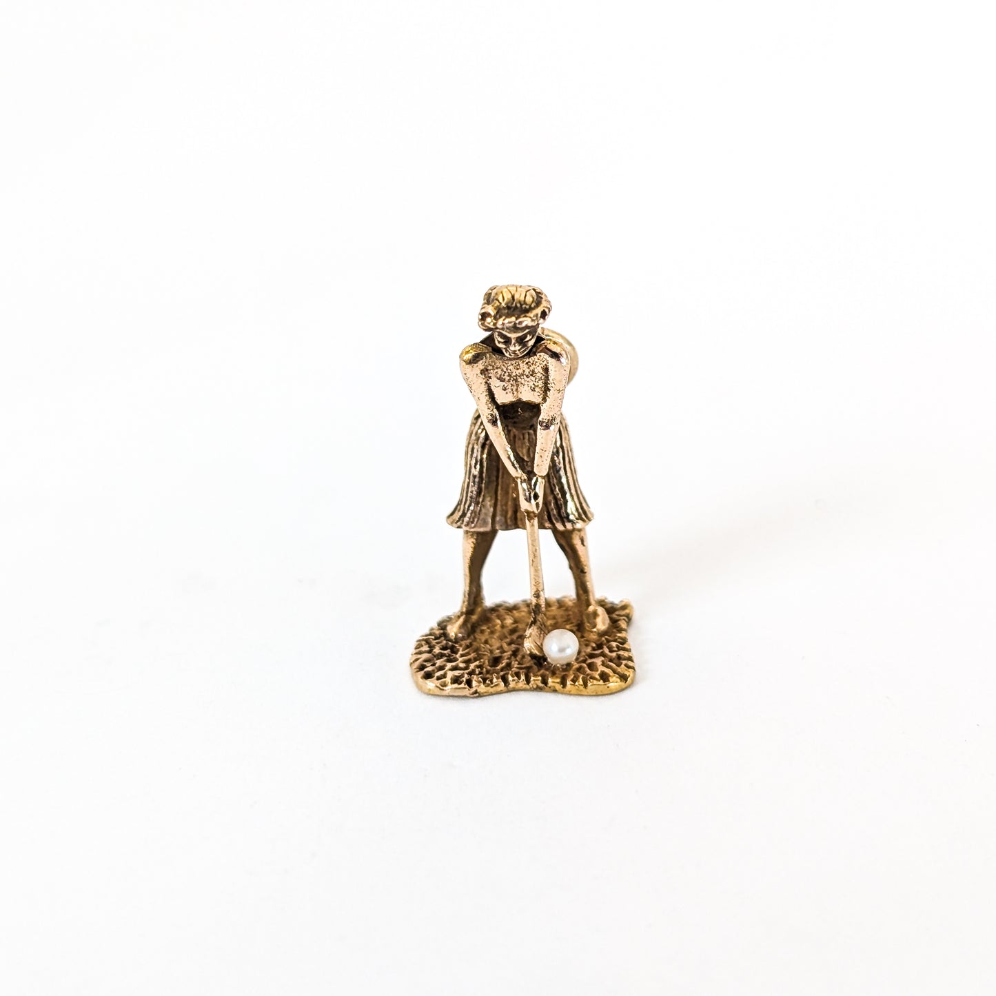 14k Gold vintage mechanical charm of lady playing golf with a pearl golf ball on a white background