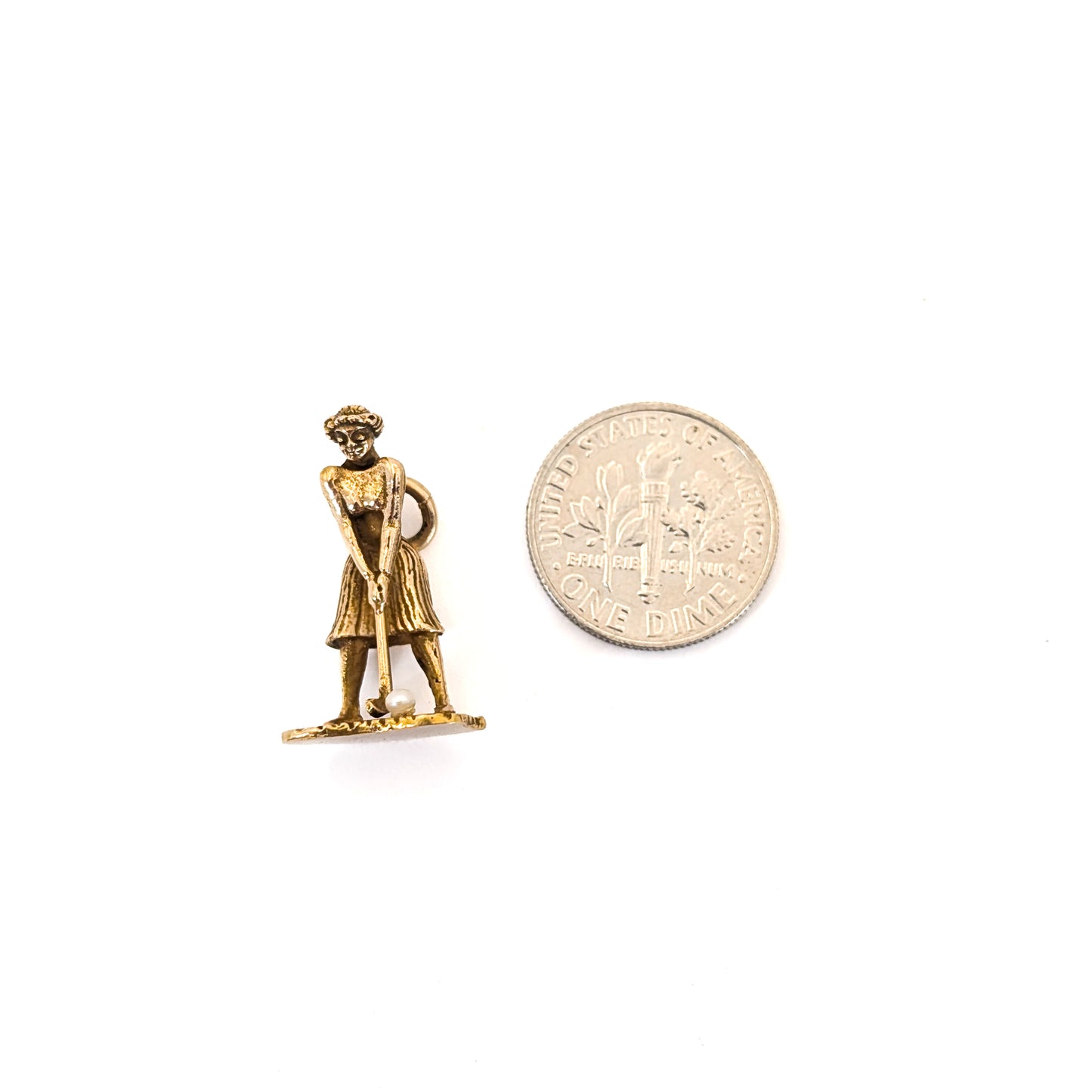 14k Gold vintage mechanical charm of lady playing golf with a pearl golf ball next to a dime on a white background