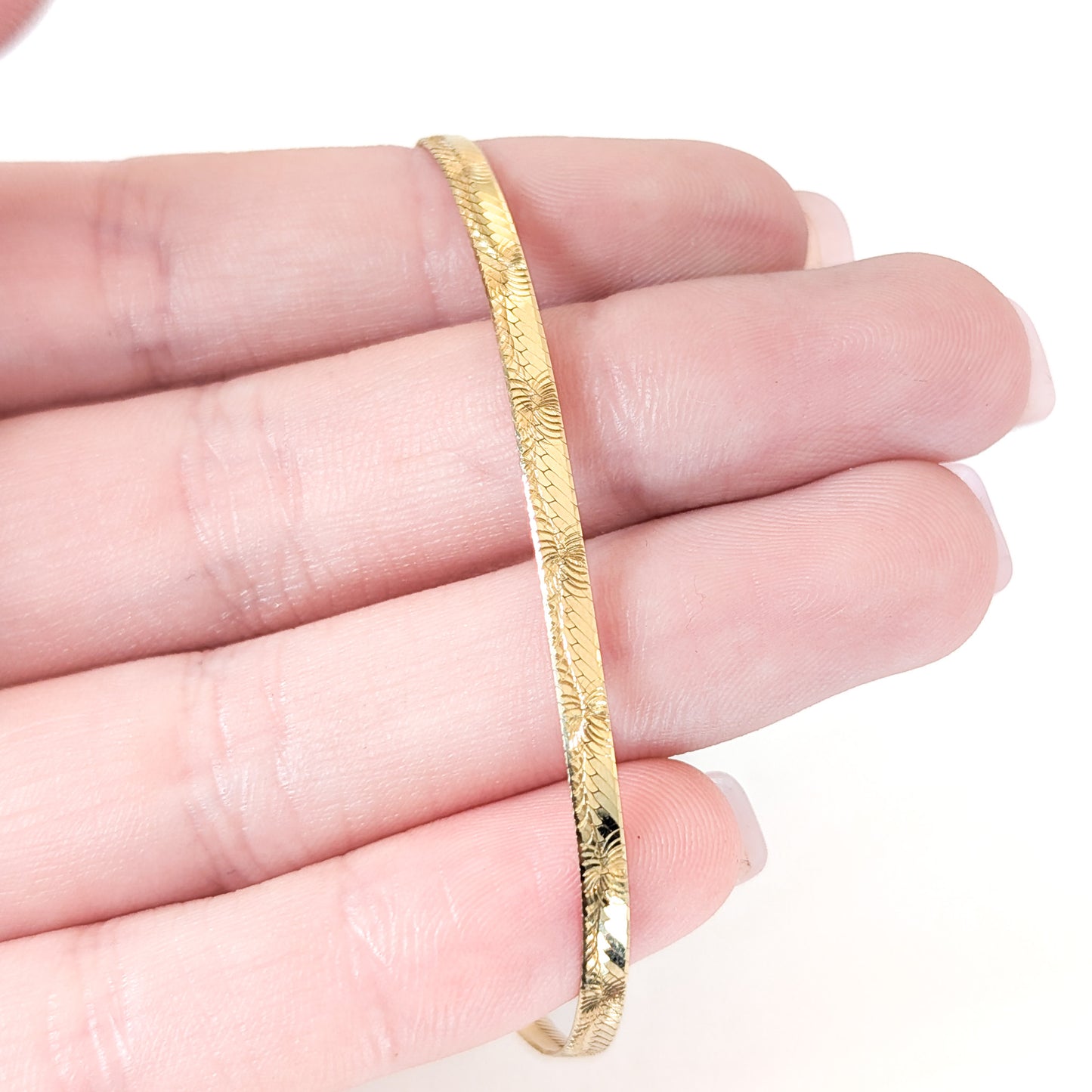 Vintage 14K gold bracelet features an elegant herringbone design with a textured finish on a white background