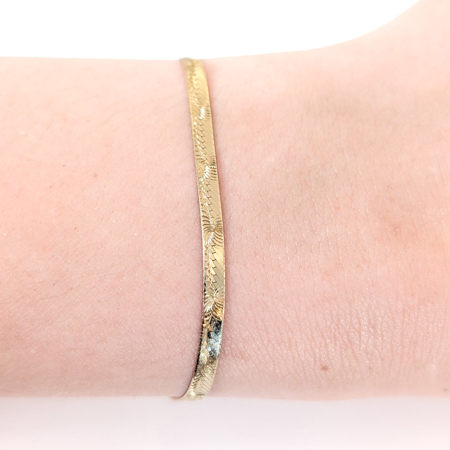 Vintage 14K gold bracelet features an elegant herringbone design with a textured finish on a white background