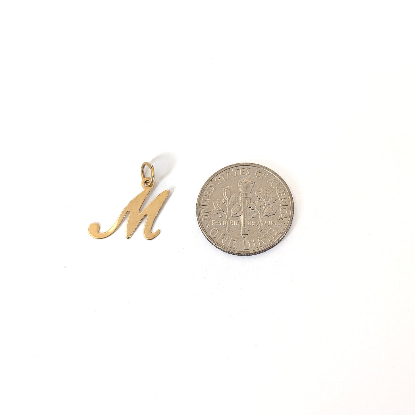 14k Gold letter 'M' pendant next to a dime on a white background