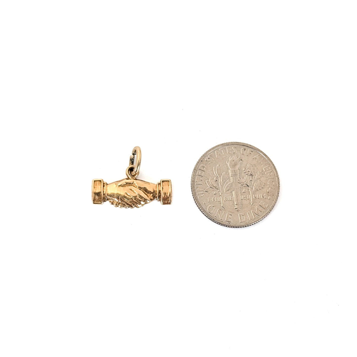 14k Gold handshake pendant next to a dime on a white background