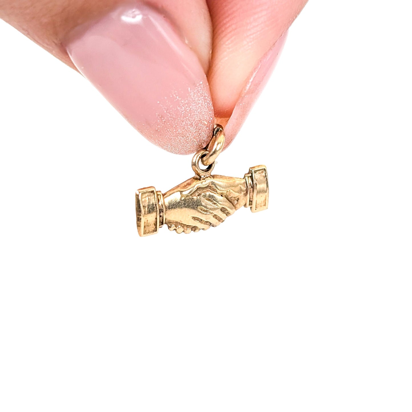 14 Gold handshake charm held between fingers on a white background