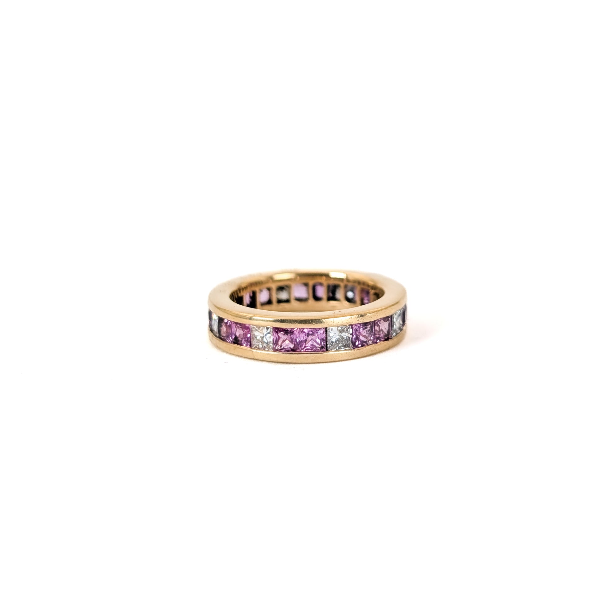 14k gold eternity band with pink sapphires and diamonds on a white background