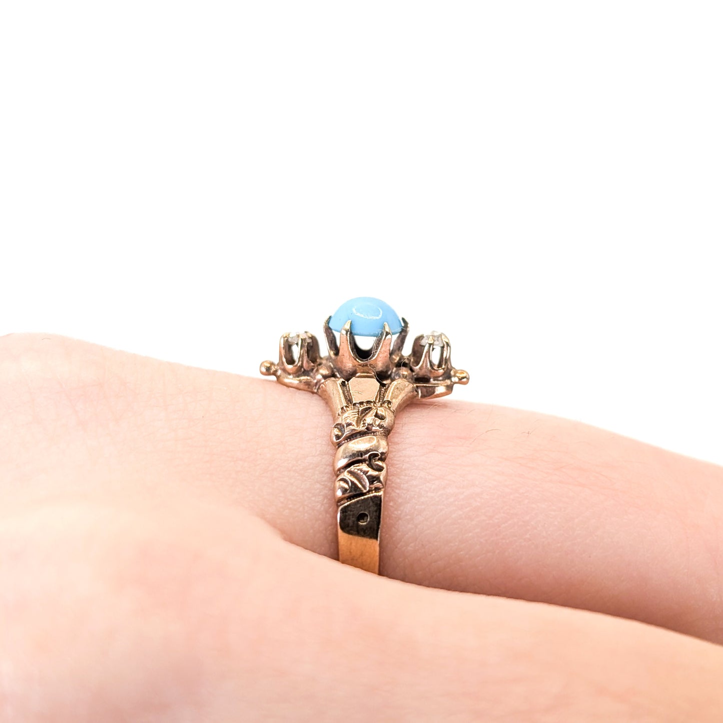 0k Vintage ring with turquoise stone and 2 rose cut diamonds on a person's finger against a white background