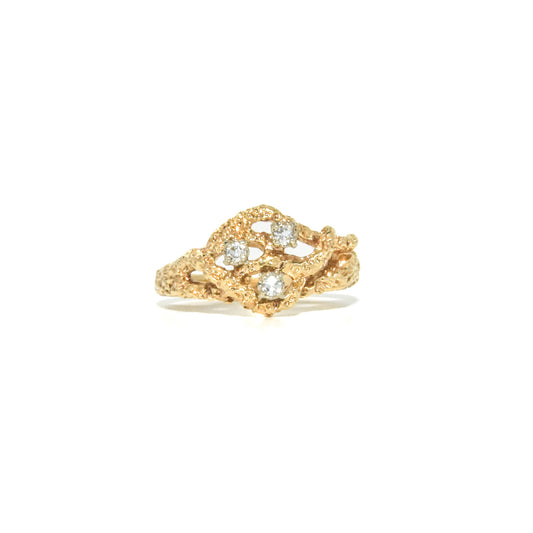 A vintage 14K gold Brutalist style ring with a textured design and three round-cut diamonds set within the gold structure.