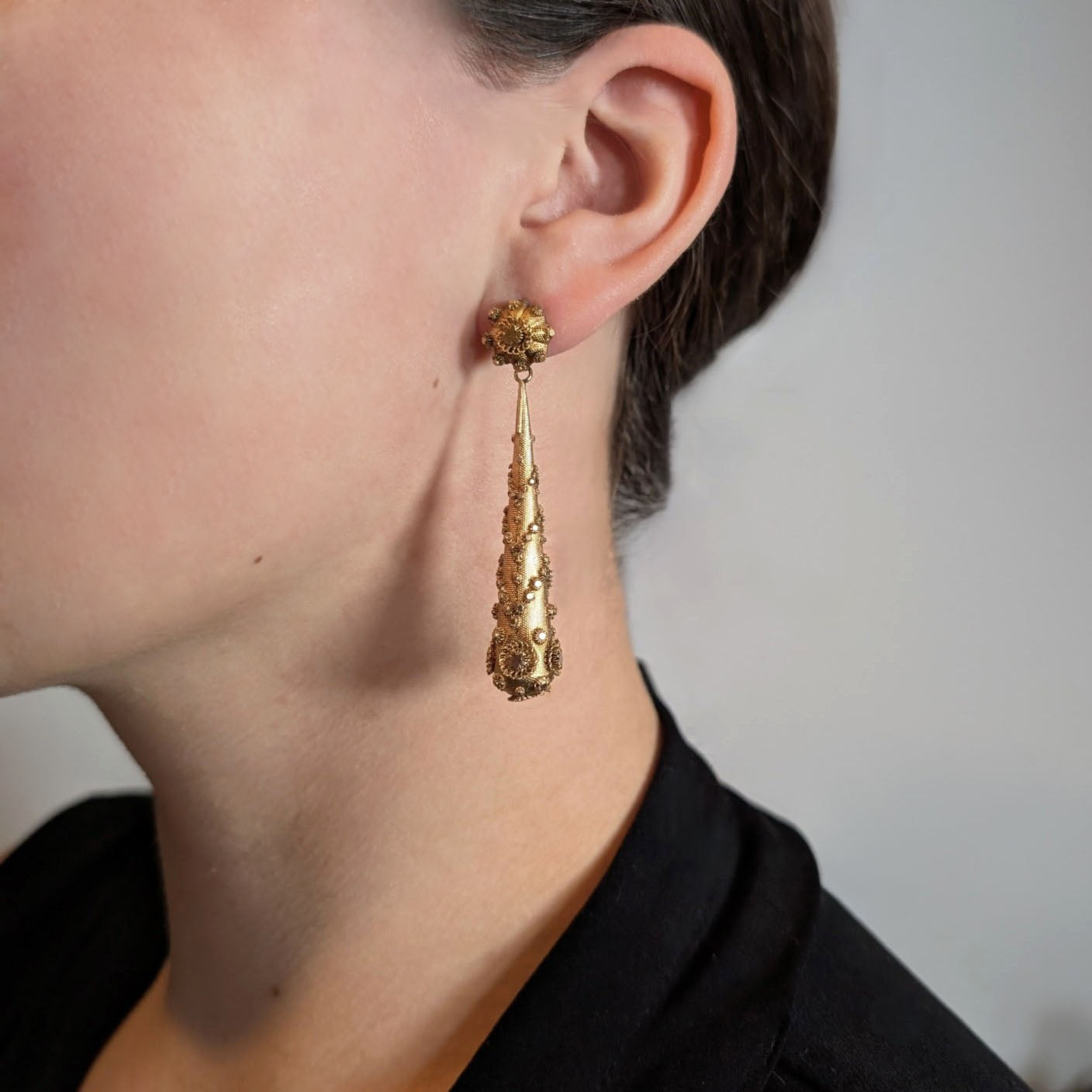 Pair of gold Georgian-era earrings with intricate designs on a lady's ears. Crafted in solid 14K yellow gold, they feature the highly skilled and delicate art of cannetille work, They are a breathtaking example of early 19th-century goldsmithing.