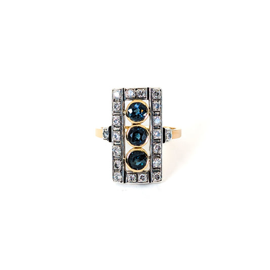 Elegant dinner ring, crafted in Italy, blends the warmth of 18K yellow gold with the cool brilliance of silver. The ring features a striking rectangular design with three deep blue sapphires, their rich color evoking the Mediterranean night sky against a white background.