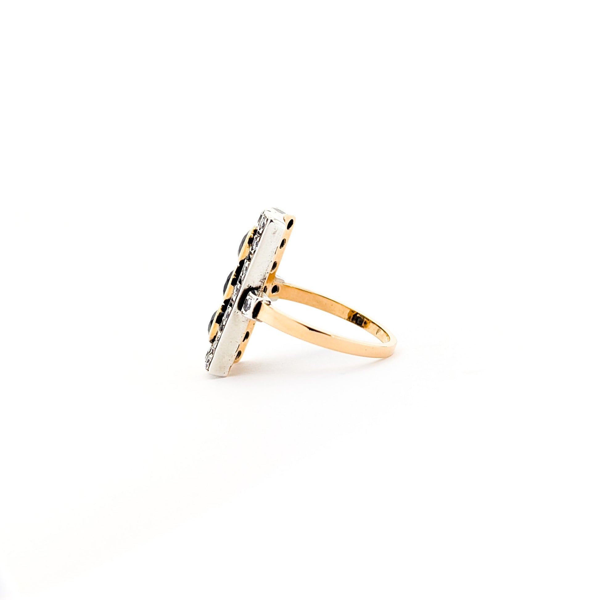 Elegant dinner ring, crafted in Italy, blends the warmth of 18K yellow gold with the cool brilliance of silver. The ring features a striking rectangular design with three deep blue sapphires, their rich color evoking the Mediterranean night sky against a white background.