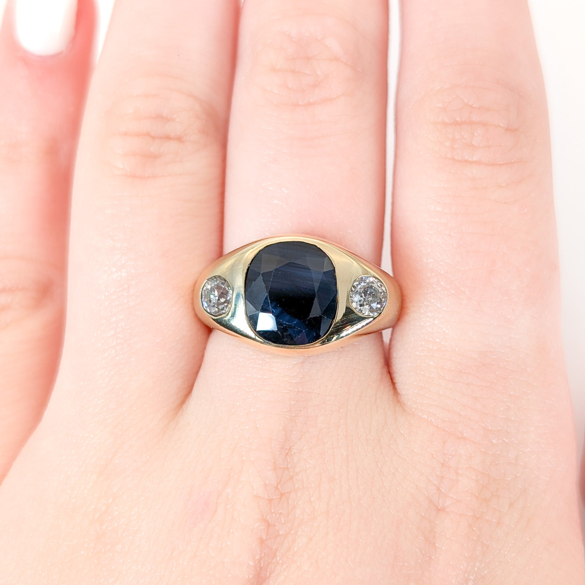 Italian crafted Antique Cushion Cut Blue Sapphire and Old Mine Cut Diamonds Dome Ring in 18K Gold with on a woman's hand white background 