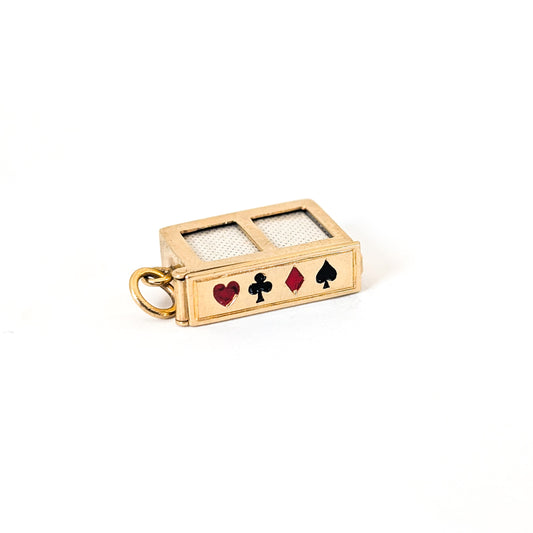 14k gold vintage mechanical charm with enameled card suit symbols and a real deck of cards on a white background