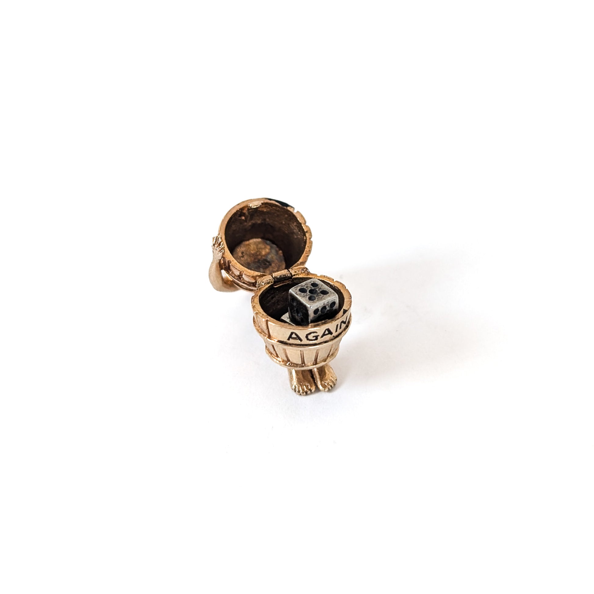 14K gold mechanical cram of a man in a barrel with 'Never Again' engraving  with two small dice inside on a white background