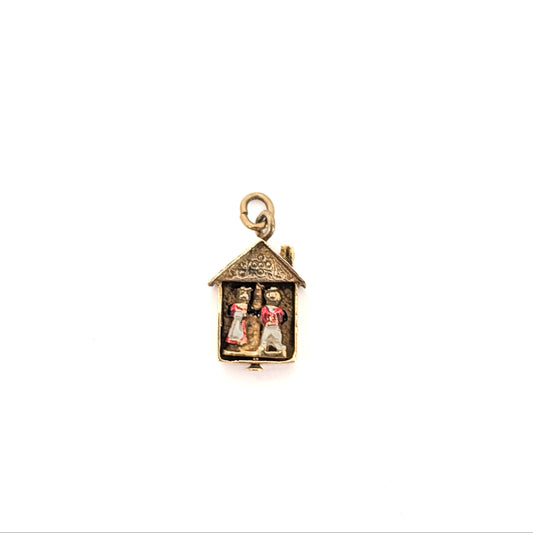 14k Gold charm with two figures inside a Weather house on a white background
