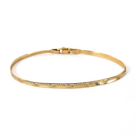 Vintage 14K gold bracelet features an elegant herringbone design with a textured finish  on a white background