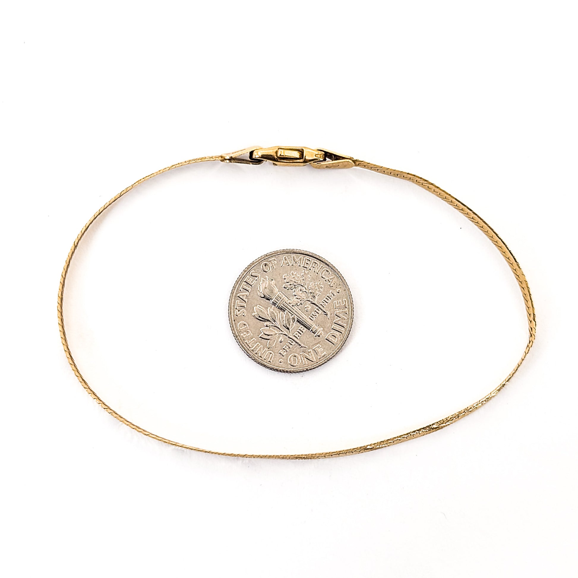 Vintage 14K gold bracelet features an elegant herringbone design with a textured finish  on a white background
