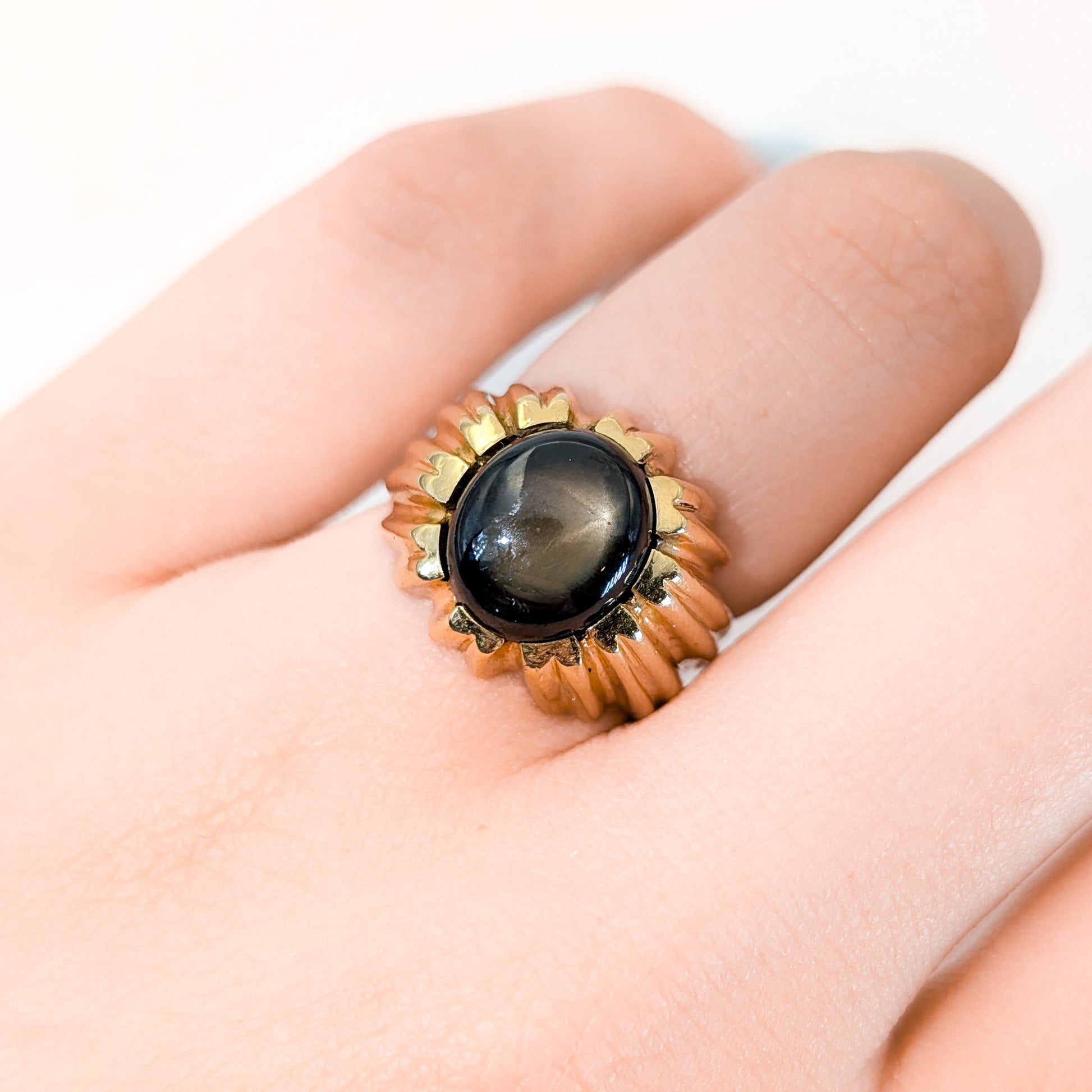 14K gold ring with a black star sapphire gemstone on a white background