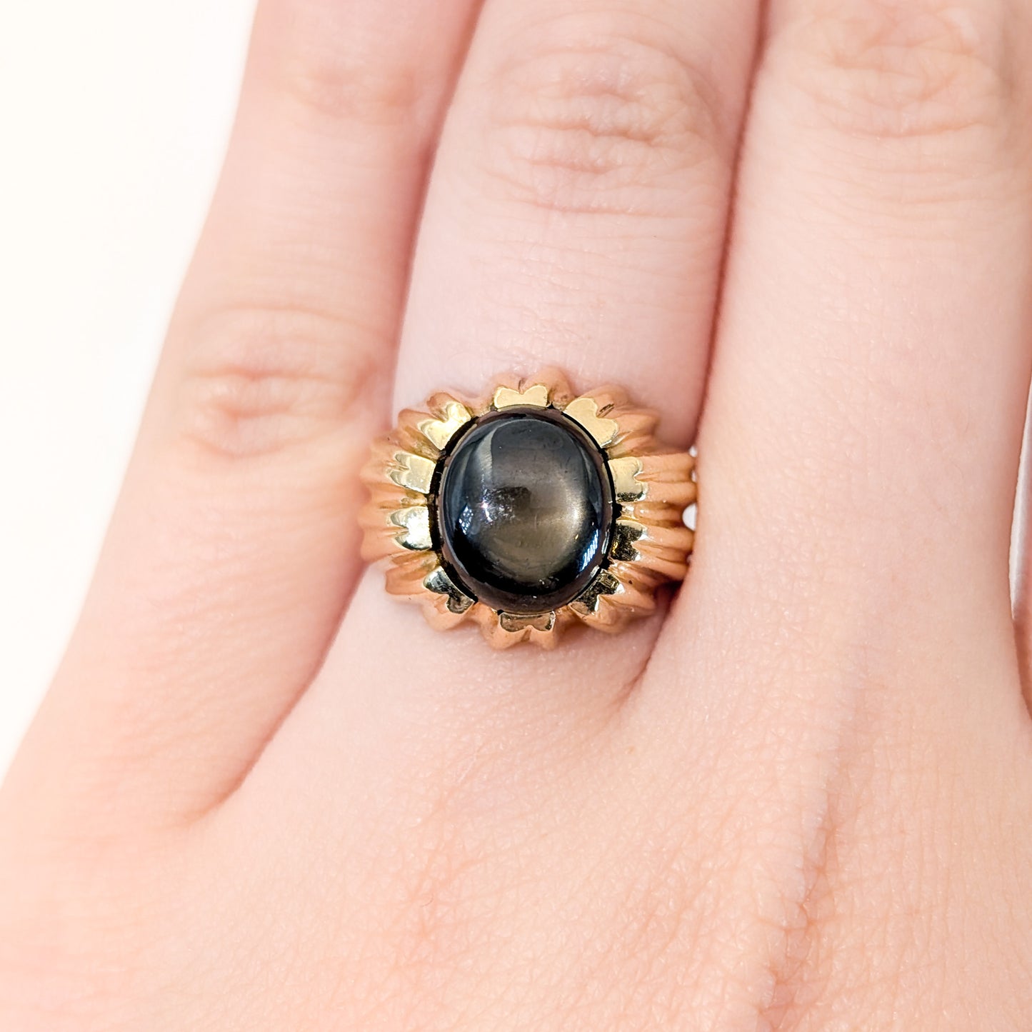 14K gold ring with a black star sapphire gemstone on a white background